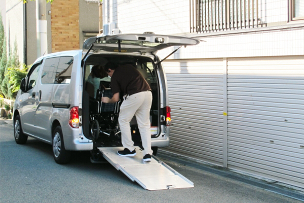 車椅子に乗っている人を車で送迎する様子